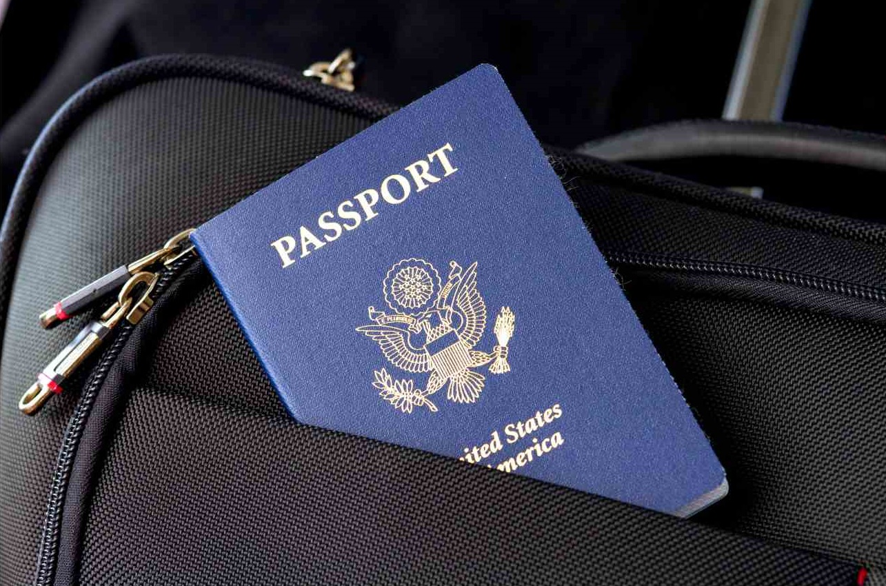 Blue passport book sticking out of a suitcase.  